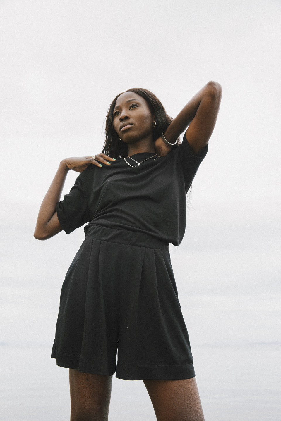 AWAN black tee and shorts against a pale sky