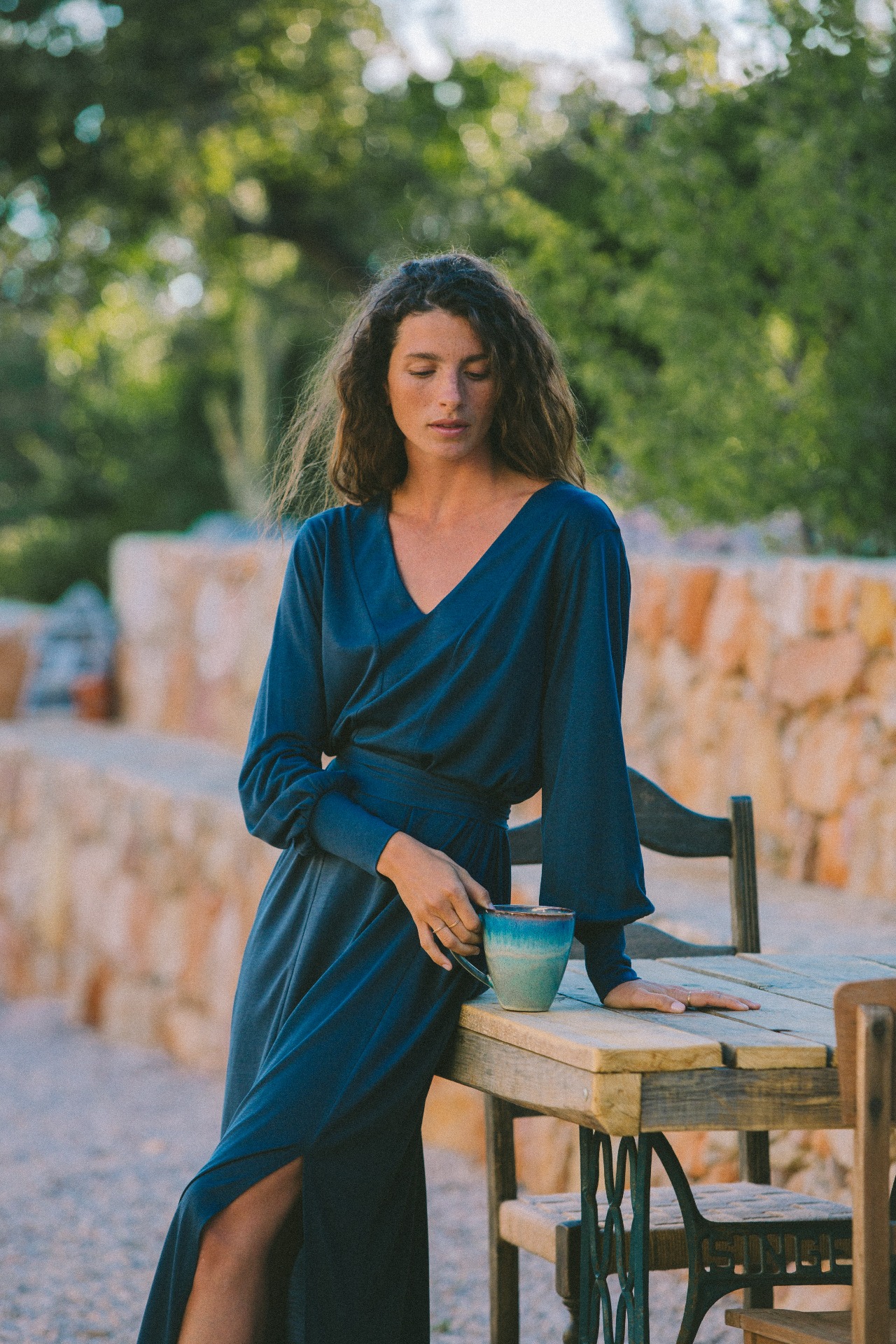 AWAN deep blue wrap dress at a stone table